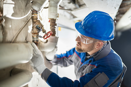 Commercial plumber inspecting a series of pipes - Boyd Plumbing